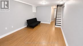 Toronto (Palmerston-Little Italy) apartment for rent - A black sofa sits in a room with wooden floors and white walls.