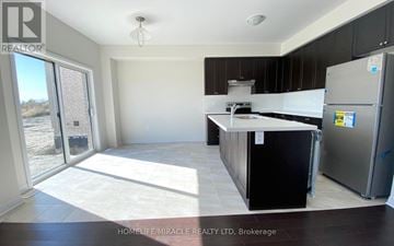 Innisfil (Alcona) apartment for rent - A kitchen with black cabinets and a refrigerator in a real estate listing.