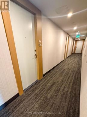 Toronto (York University Heights) condo for rent - A hallway with doors on both sides and a green exit sign above the door on the right.