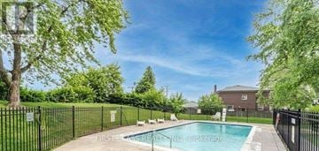 Toronto (Keelesdale-Eglinton West) condo for rent - A pool surrounded by a black fence with trees in the background.