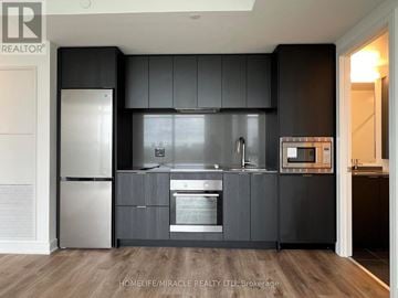 Mississauga (Cooksville) condo for rent - A modern kitchen with dark grey cabinets and stainless steel appliances.