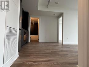 Mississauga (Cooksville) condo for rent - A spacious room with wooden flooring and white walls, with a door leading to another room.
