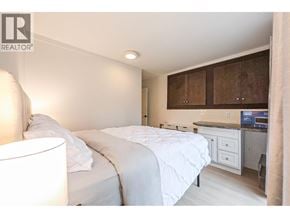 Vancouver apartment for rent - A bedroom with a white bed and a small kitchenette.