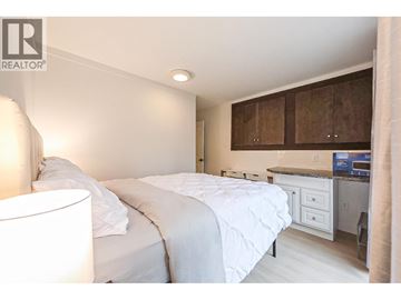 Vancouver apartment for rent - A bedroom with a white bed and a small kitchenette.