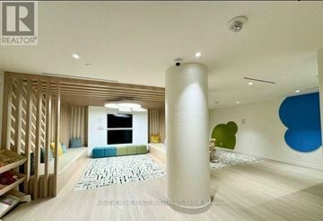 Toronto (Regent Park) condo for rent - A living room with a white column in the middle and a blue chair on the right.