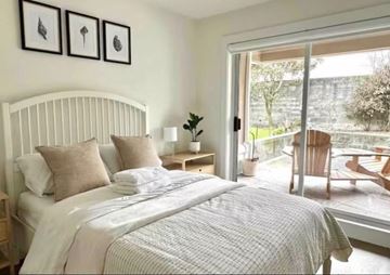 White Rock apartment for rent - A bedroom with a large bed and a view of a garden outside.
