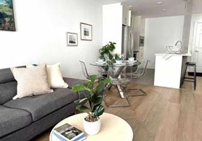 White Rock apartment for rent - A living room with a grey couch, a coffee table, and a dining table set up.