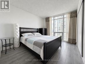 Toronto (Waterfront Communities) condo for rent - A bedroom with a large bed and a view of a building outside the window.