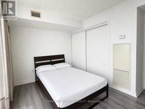 Toronto (Waterfront Communities) condo for rent - A bedroom with a bed, wooden headboard, and a white mattress.