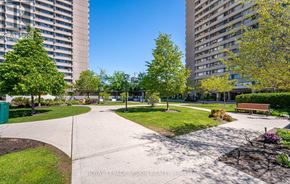 Toronto (Flemingdon Park) condo for rent - A park with a bench, trees, and apartment buildings in the background.