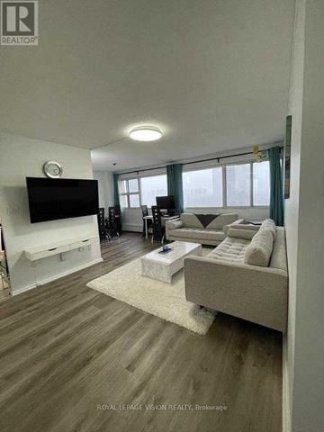 Toronto (Flemingdon Park) condo for rent - A living room with a grey couch and a flat screen TV.