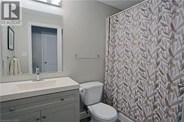 Kitchener condo for rent - A bathroom with a toilet, sink, and shower curtain.