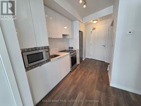 Toronto (Niagara) condo for rent - A kitchen with white cabinets and a microwave above the stove.