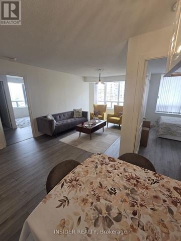 Toronto (Willowdale West) condo for rent - A living room with a couch, chairs, and a dining table with a floral tablecloth.
