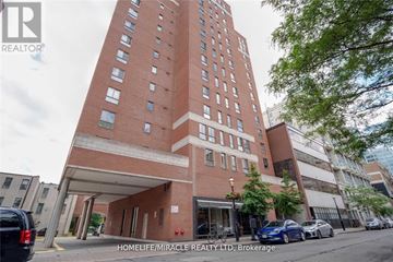 Toronto (Church-Yonge Corridor) condo for rent - A tall red brick building with a parking lot in front.