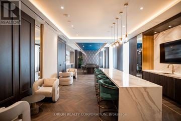 Vaughan (Vaughan Corporate Centre) condo for rent - A modern living room with a long white marble table and green chairs.