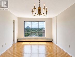Mississauga (Applewood) condo for rent - A large, empty room with a chandelier and a view of the city through a large window.