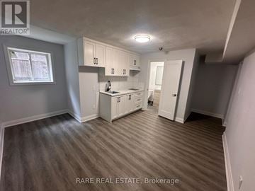 Toronto (Casa Loma) multi-family for rent - A kitchen area with white cabinets and a window.