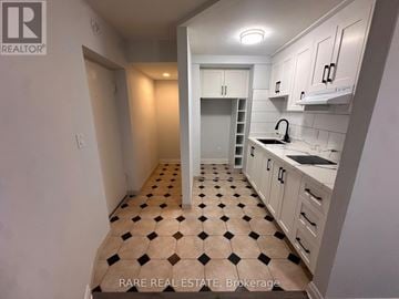 Toronto (Casa Loma) multi-family for rent - A kitchen with white cabinets and a checkered floor.