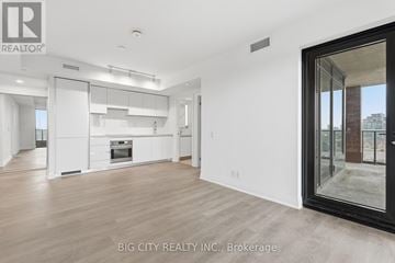 Toronto (Leaside) condo for rent - A spacious, well-lit kitchen with white cabinets and a large island.
