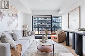 Toronto (Thorncliffe Park) condo for rent - A living room with a grey couch, a coffee table, and a large window with a view of a building.