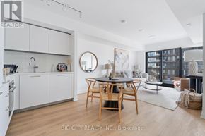 Toronto (Thorncliffe Park) condo for rent - A modern kitchen with white cabinets and a wooden dining table.