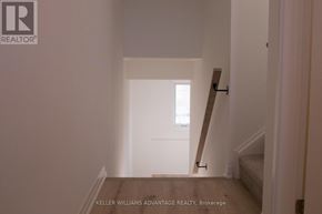 New Tecumseth (Tottenham) townhouse for rent - A hallway with a wooden floor and white walls leading to a door.