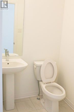 New Tecumseth (Tottenham) townhouse for rent - A white toilet sits next to a white sink in a bathroom.
