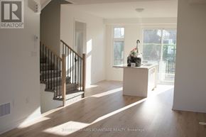 New Tecumseth (Tottenham) townhouse for rent - A large, empty room with a staircase and a table with a vase on it.