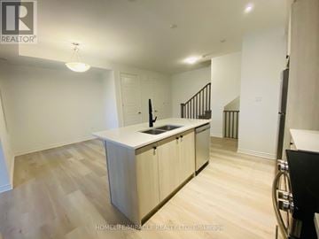 Barrie townhouse for rent - A kitchen with wooden floors and cabinets, a sink, and a stove top oven.