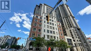 Hamilton (Central) condo for rent - A tall building with a crane on top and a traffic light with a red hand.