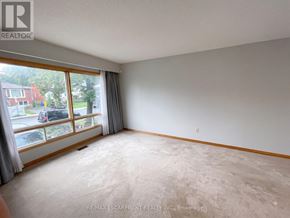 Hamilton (Eastmount) apartment for rent - A room with a large window and a view of a street with cars and houses.