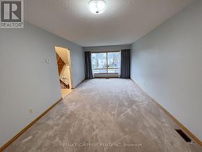 Hamilton (Eastmount) apartment for rent - A spacious room with a carpeted floor and a doorway leading to another room.
