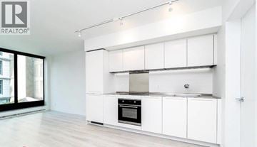 Vancouver apartment for rent - A modern kitchen with white cabinets and a stainless steel range hood.