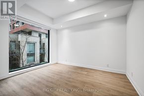 Toronto (Thorncliffe Park) condo for rent - A spacious room with wooden flooring and white walls, with a view of a building outside the window.