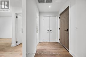 Toronto (Thorncliffe Park) condo for rent - A hallway with white walls and wooden floors, leading to a door on the right.