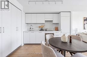 Toronto (Thorncliffe Park) condo for rent - A modern kitchen with white cabinets and a wooden table.