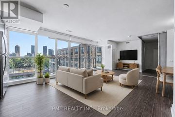 Toronto (Niagara) condo for rent - A living room with a couch, chairs, and a television with a city view through the window.