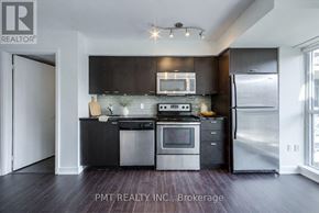 Toronto (Niagara) condo for rent - A modern kitchen with dark wood floors and stainless steel appliances.