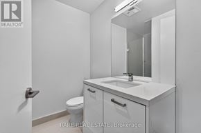 Toronto (Waterfront Communities) condo for rent - A white bathroom with a toilet, sink, and mirror.