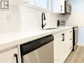 Brantford apartment for rent - A kitchen with white cabinets and a black dishwasher.
