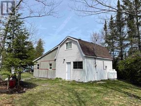 Goulais River apartment for rent - A small white house with a grey roof is surrounded by trees.