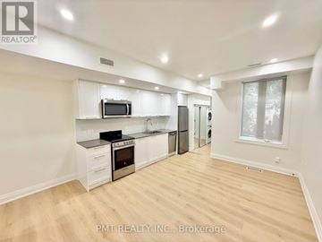 Toronto (Little Portugal) apartment for rent - A well-lit kitchen with white cabinets and a wooden floor.