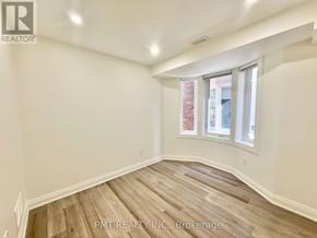 Toronto (Little Portugal) apartment for rent - A room with wooden flooring and a window showing a brick building outside.