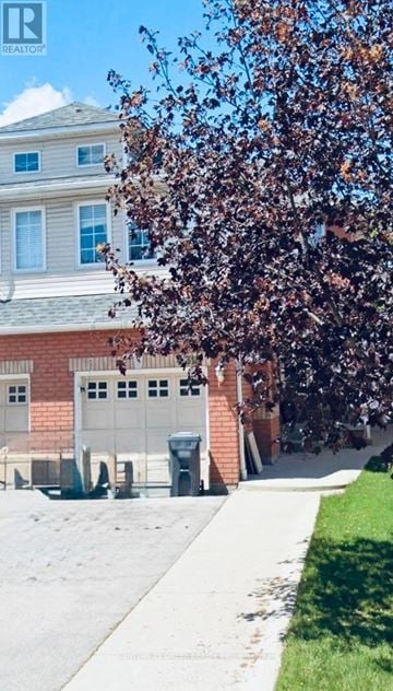 Mississauga (Meadowvale Village) apartment for rent - A tree with brown leaves is in front of a building with a garage door.