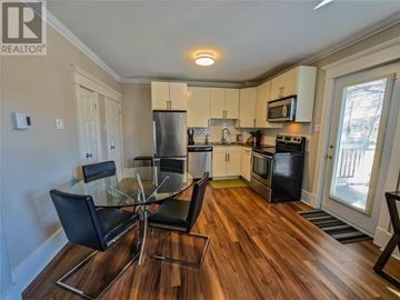 St. John's multi-family for rent - A modern kitchen with a glass table and black chairs.