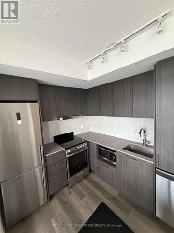 Vaughan (Vaughan Corporate Centre) condo for rent - A modern kitchen with stainless steel appliances and wooden cabinets.