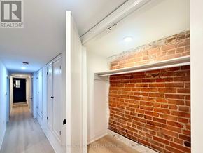 Toronto (University) apartment for rent - A long hallway with white walls and a brick wall on the side.