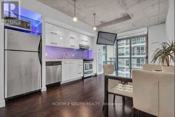 Toronto (Waterfront Communities) condo for rent - A modern kitchen with stainless steel appliances and a dining table with chairs.