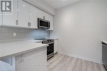 Hamilton (Ancaster) townhouse for rent - A kitchen with white cabinets and a microwave above the stove.